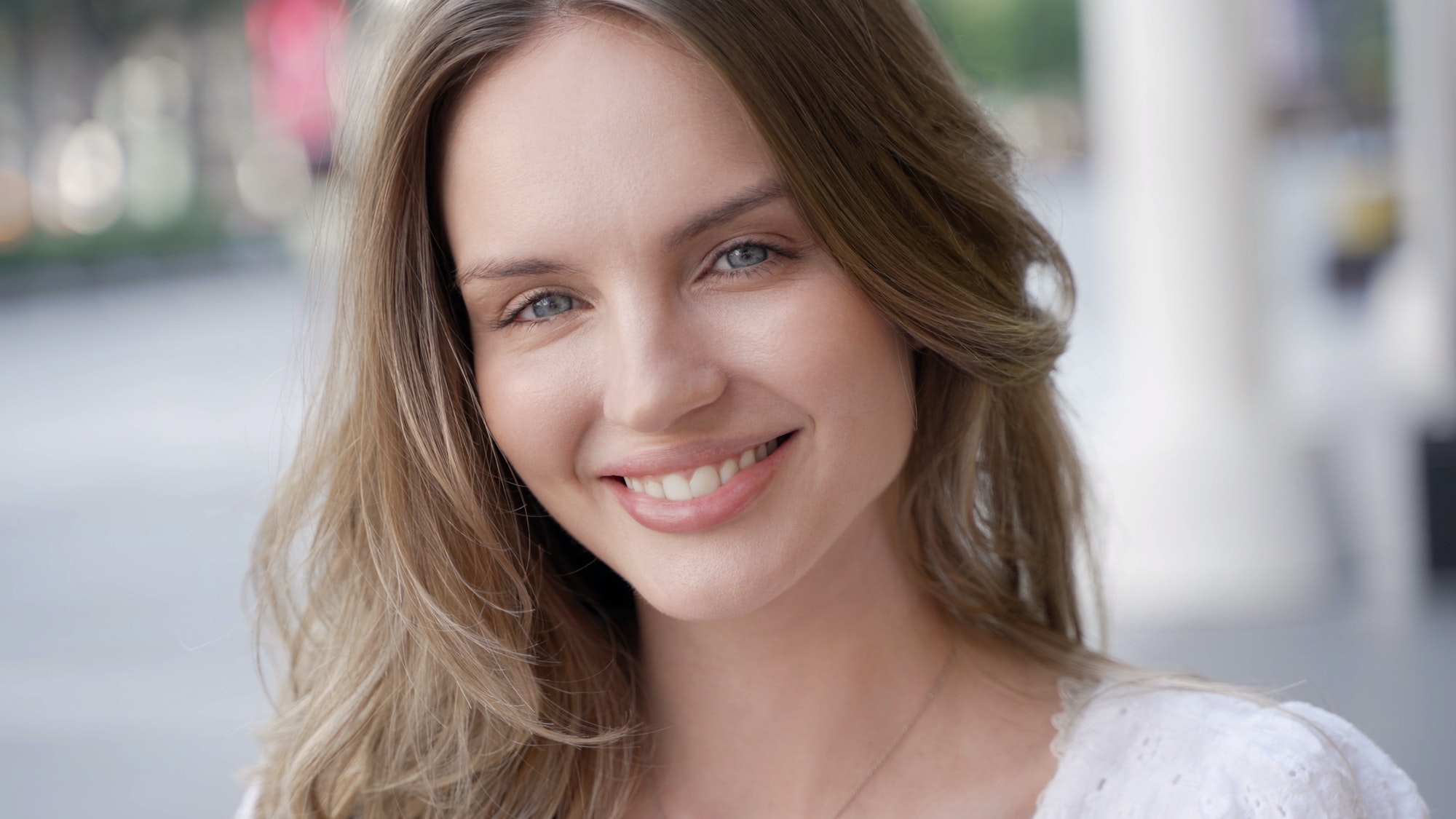 A smiling young adult with long hair in a headshot portrait